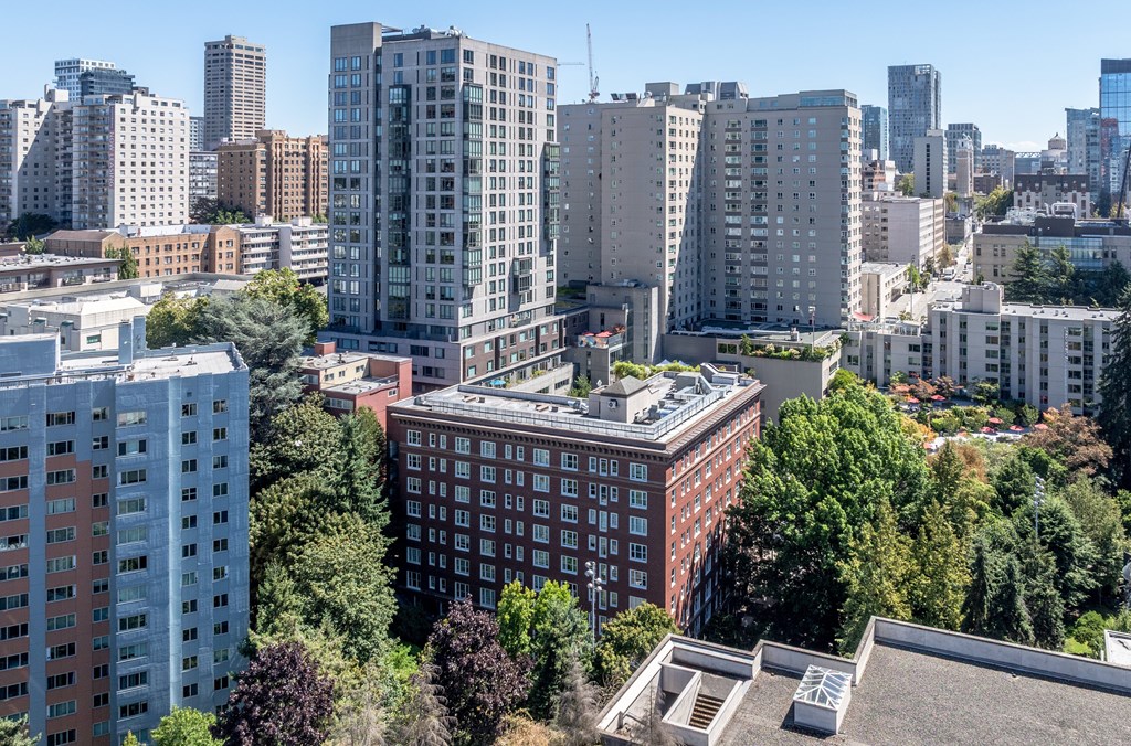 A cityscape with a mix of modern and older buildings, with trees interspersed throughout.
