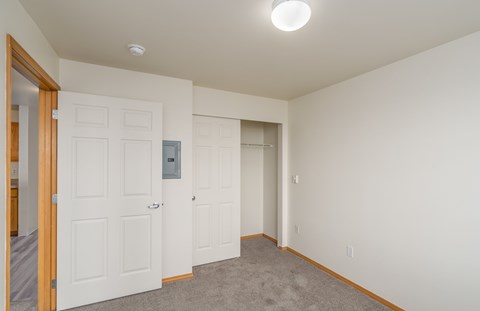 A room with a white door and a grey carpet.