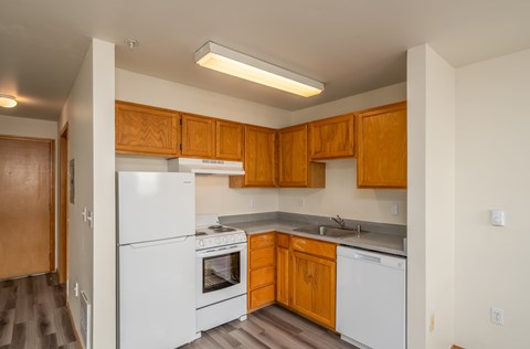 A kitchen with white appliances and wooden cabinets.