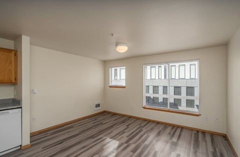 A room with wooden flooring and a window showing a building outside.