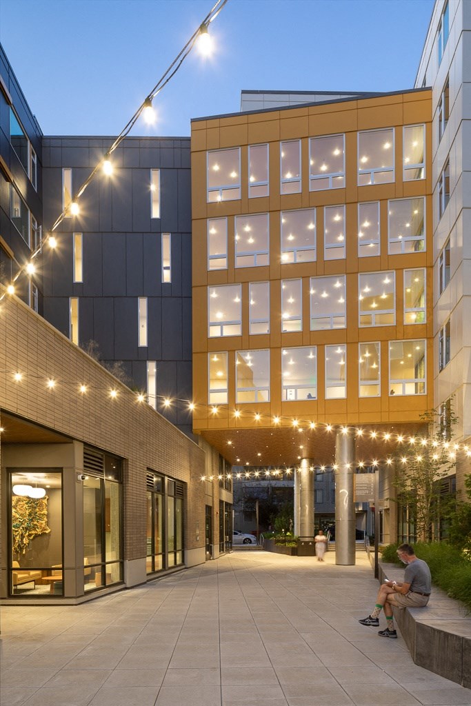 a man sits on a bench outside of a building with lights
