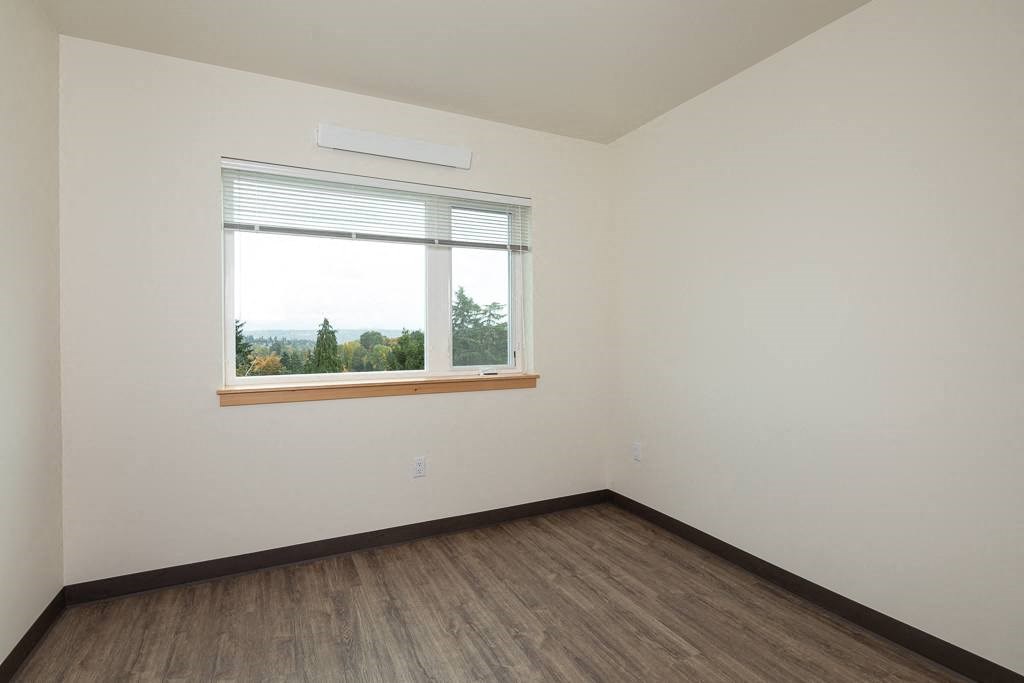 an empty room with a window and wooden floors