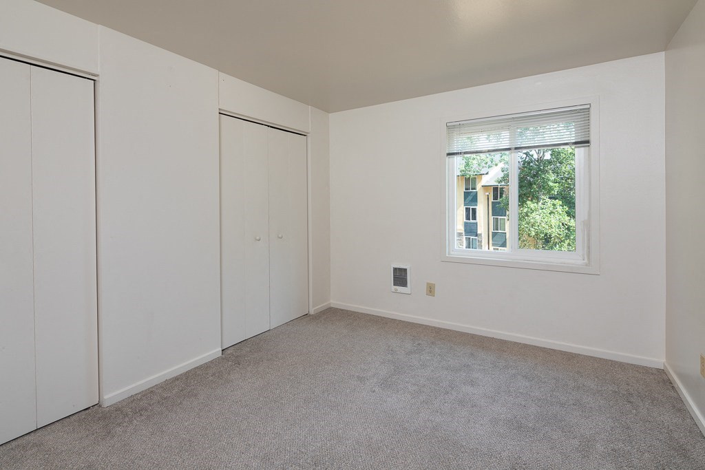 a bedroom with white walls and a window and a closet