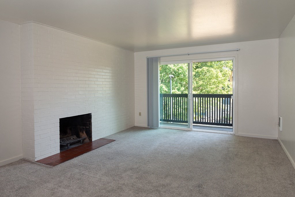 an empty living room with a fireplace and a balcony