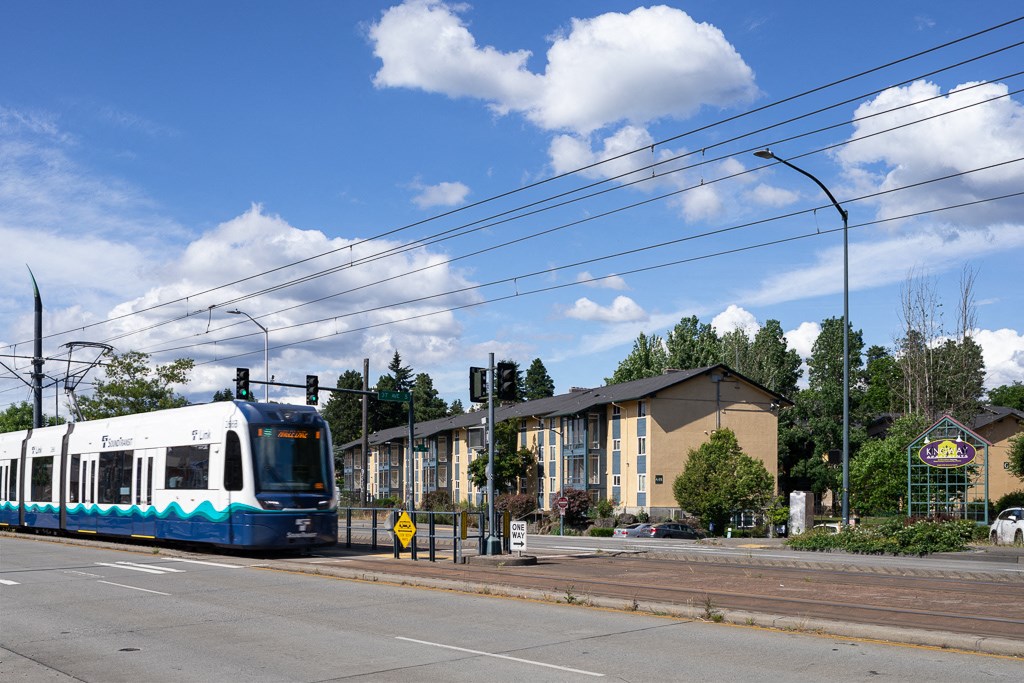 a blue and white train on the tracks near a street with a building