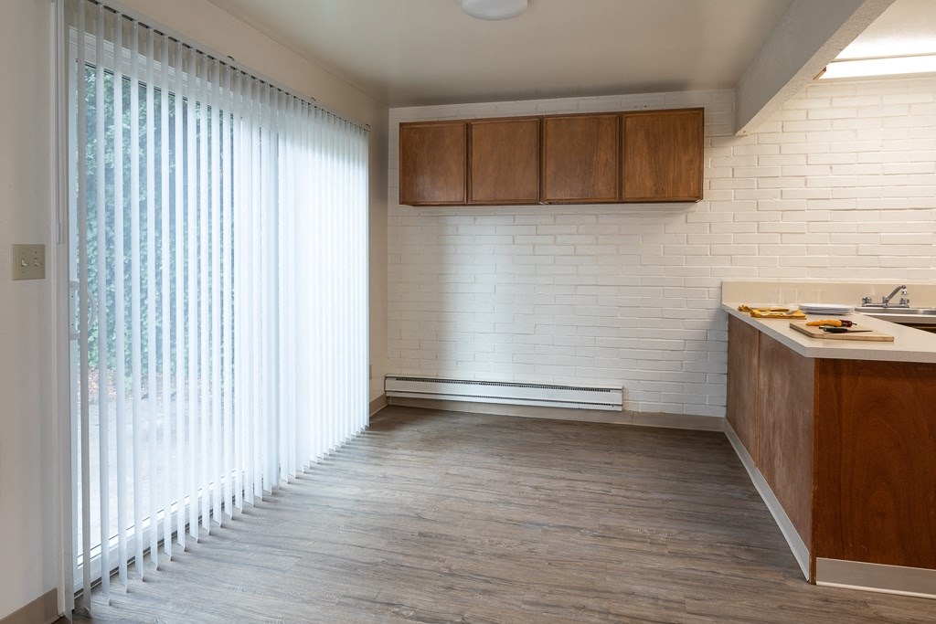 an empty kitchen with a large window and wood flooring