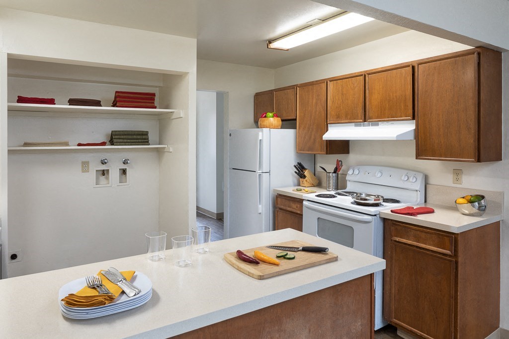 A kitchen with a white refrigerator, white stove, and brown cabinets.