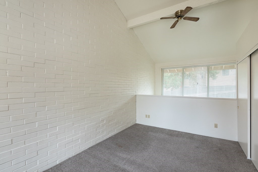 an empty living room with a ceiling fan and a window
