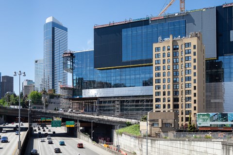 A city street with cars and a large building under construction.
