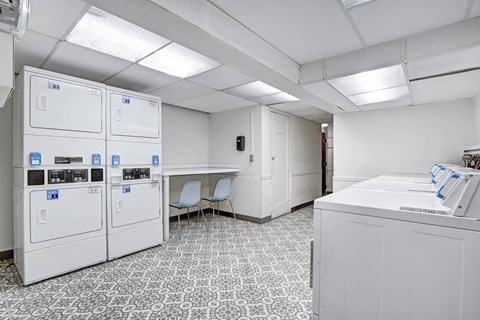A clean, white-walled room with a patterned floor and a row of white cabinets.