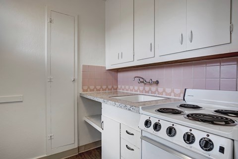 A kitchen with a white stove and white cabinets.