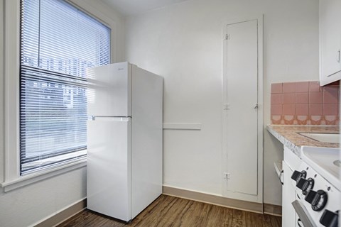 A kitchen with a white refrigerator, white oven, and a pink tile backsplash.