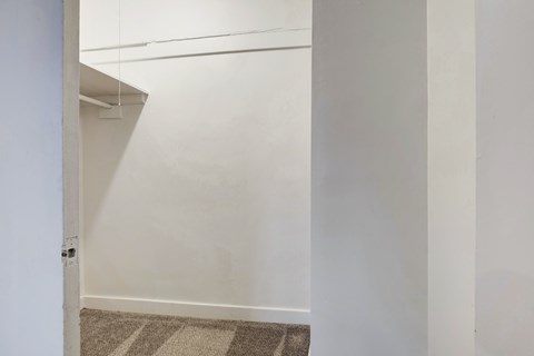 A white wall with a door on the left and a carpet on the floor.
