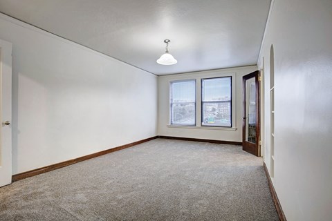 A room with a carpeted floor and a window overlooking a cityscape.