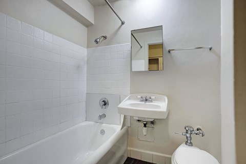 A white bathroom with a tub, sink, and toilet.