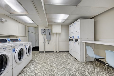 A laundry room with washers and dryers and a white cabinet.