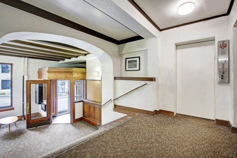 A hallway with a bench, a staircase, and a door with a sign on it.