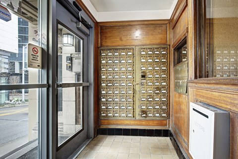 A wooden door with a glass panel and a trash can to the right.