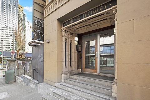 The front of a hotel with a glass door and steps leading up to it.