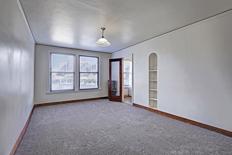 A room with a carpeted floor, a window, and a door.