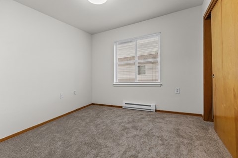 A room with a window and a carpeted floor.