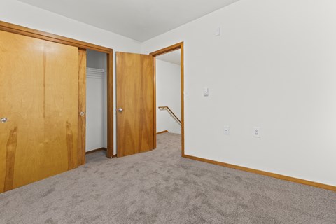 A room with a carpeted floor and two wooden doors.