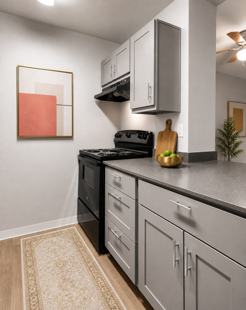 A kitchen with a black oven and grey cabinets.