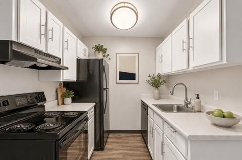 A modern kitchen with black appliances and white cabinets.
