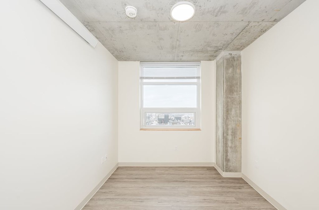 A room with a window and a concrete pillar.