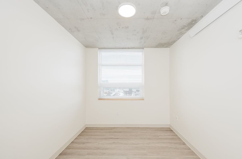 A room with a window and wooden flooring.