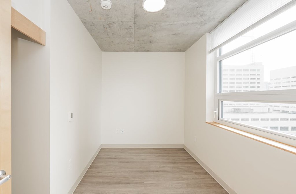 A room with a window and a wooden floor.