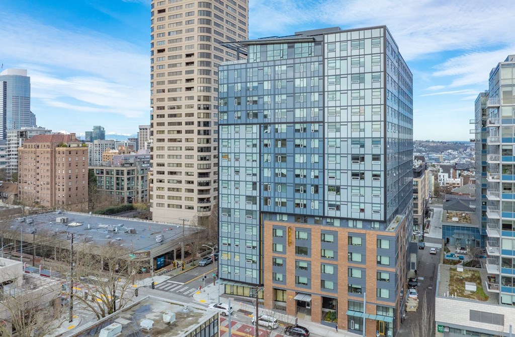 A modern glass building stands in the foreground of a cityscape.