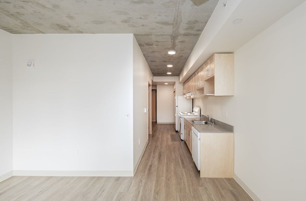 A kitchen with white walls and wooden floors.