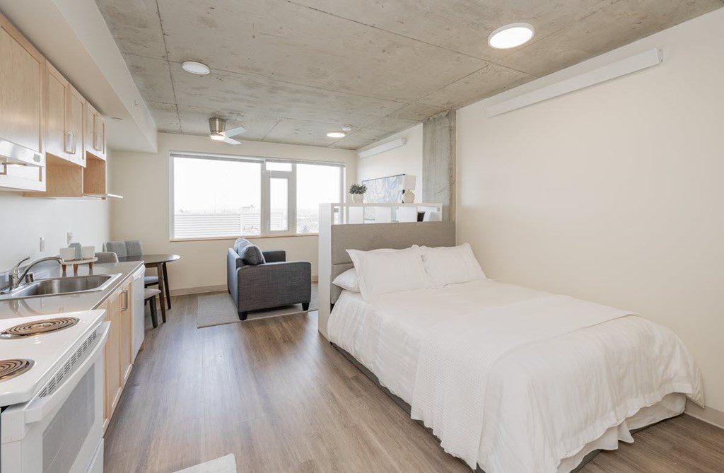 A modern bedroom with a large bed and a kitchen area.