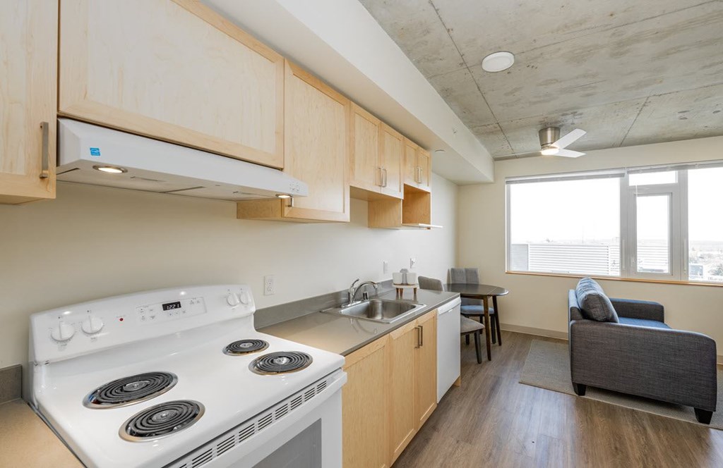 A kitchen with a stove top oven and a couch.