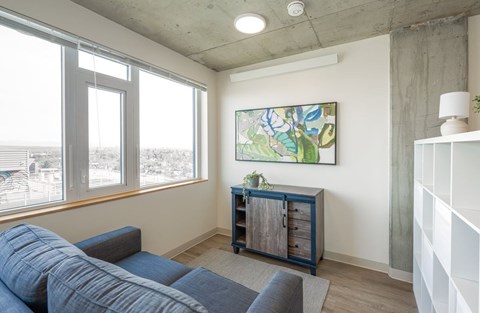 A living room with a blue couch and a painting on the wall.