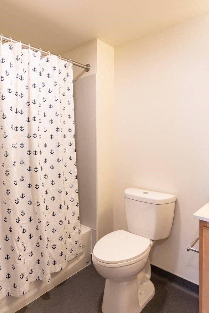 a bathroom with a toilet and a shower curtain at Arbora Court, Seattle, Washington