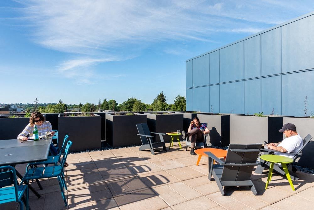 people sitting at tables and chairs on a roof terrace at Arbora Court, Washington, 98105
