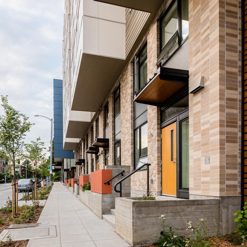 the facade of a building with orange doors and a sidewalk at Arbora Court, Washington