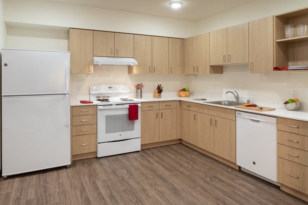 A kitchen with white appliances and wooden cabinets.