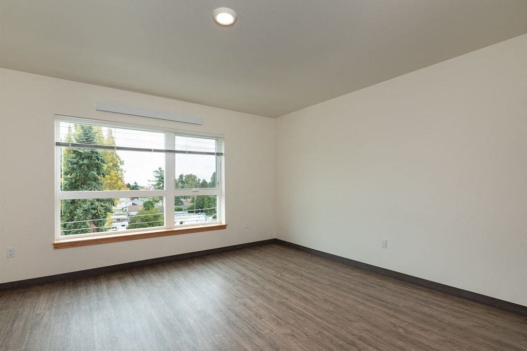 A room with a large window and wooden flooring.