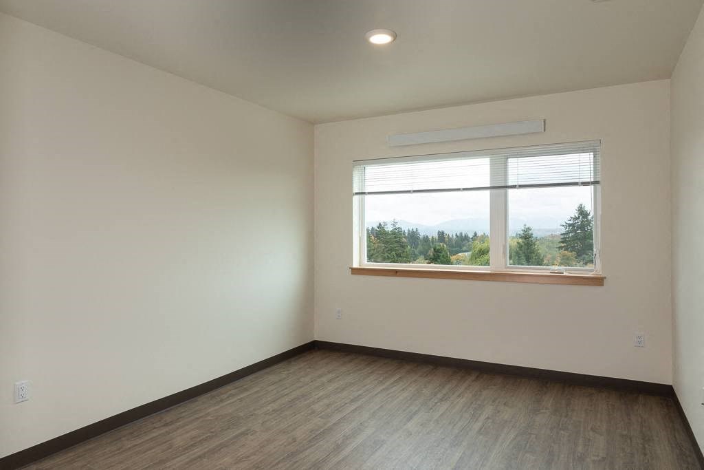 A room with a window overlooking a forest.