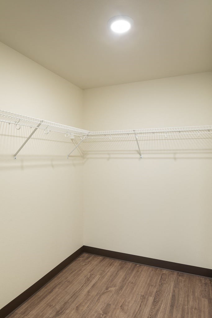 A white wall with a wooden floor and a white shelf.