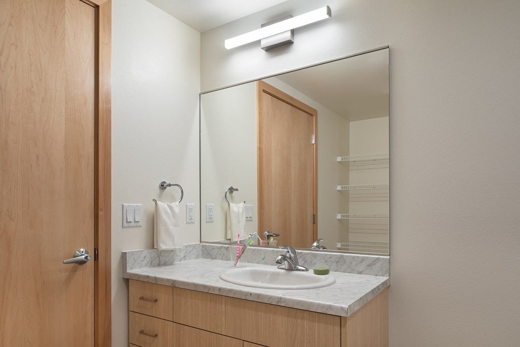 A bathroom with a sink, mirror, and light.