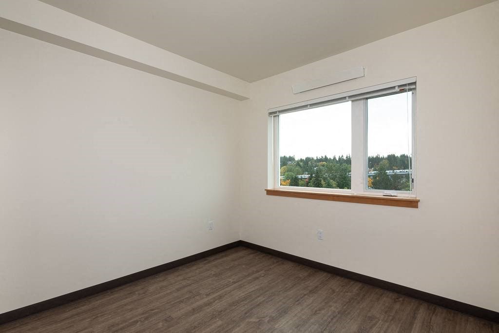 Empty room with a window overlooking a tree-filled landscape.