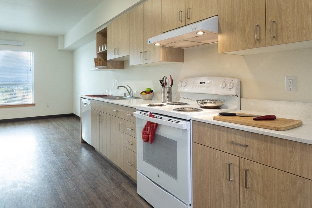 A kitchen with a white oven and wooden cabinets.
