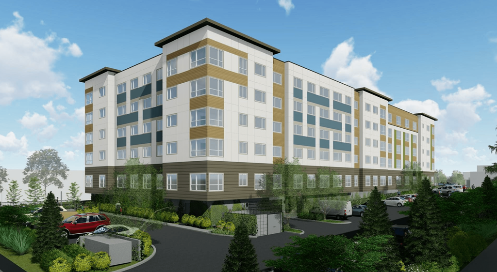 A modern multi-story building with a parking lot in front.