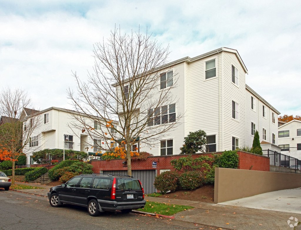 a white apartment building with a black car parked in front