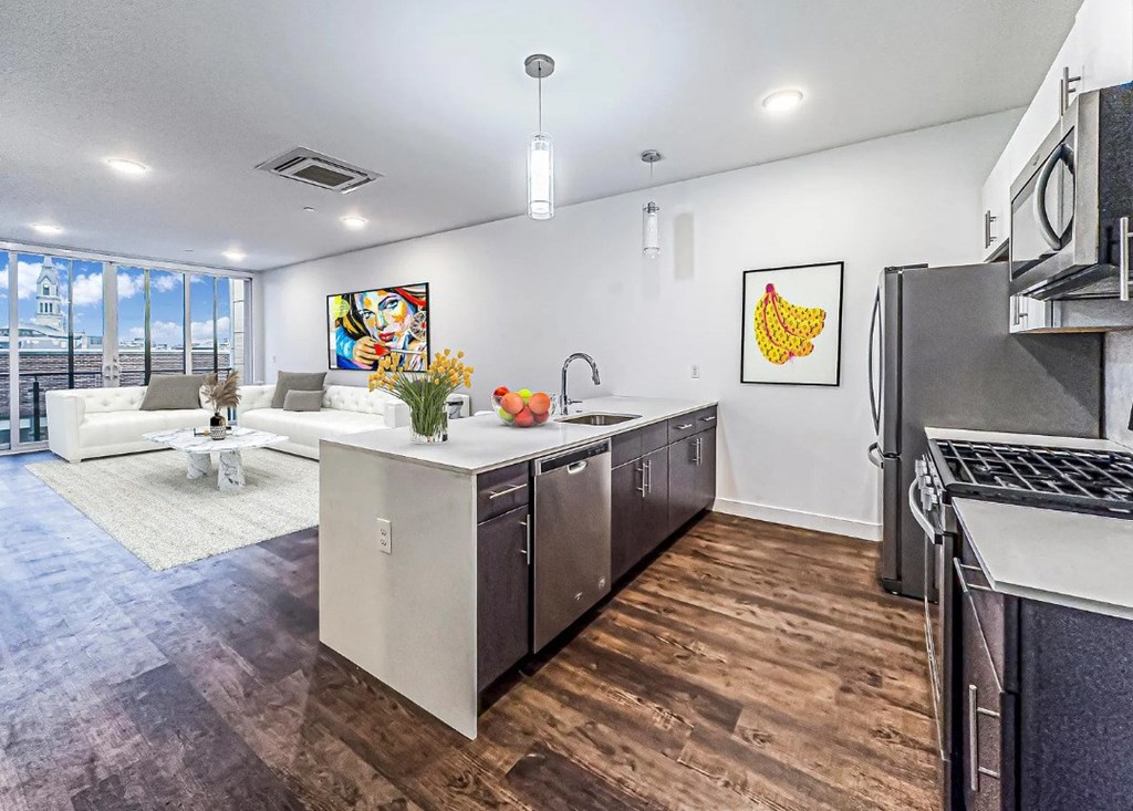 A kitchen with a white countertop and a white couch in the background.