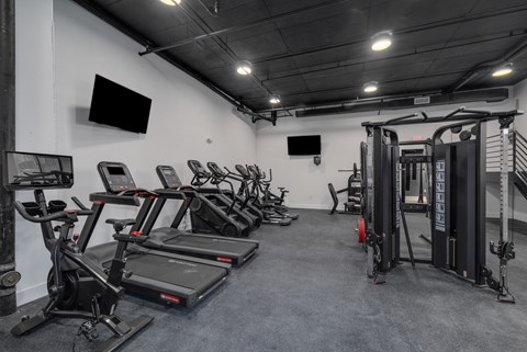 A gym with treadmills, exercise bikes, and a weight rack.